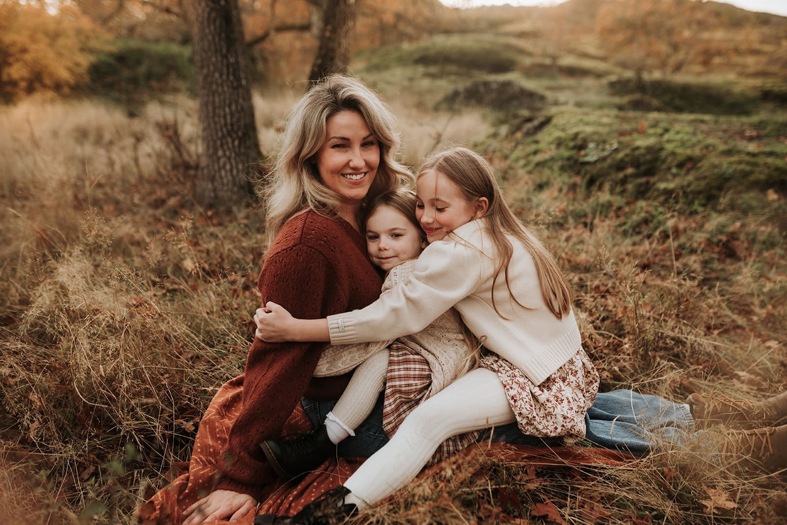 Mom and her two daughters sitting on her lap and hugging her