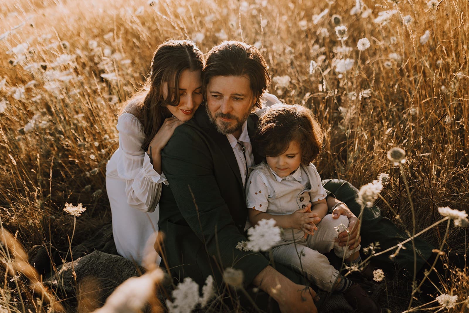 Mom, dad, and son having three wedding photo taken during golden hour in a field