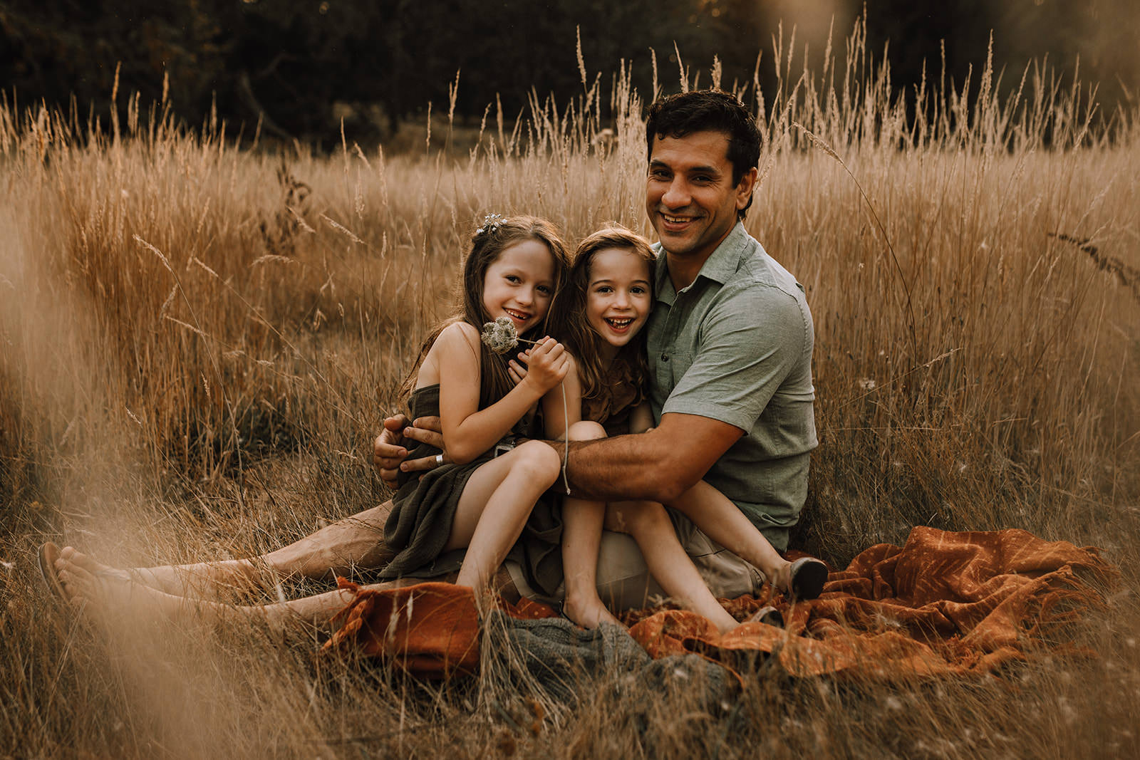 dad and daughters cuddling in the fall light of Vancouver Island